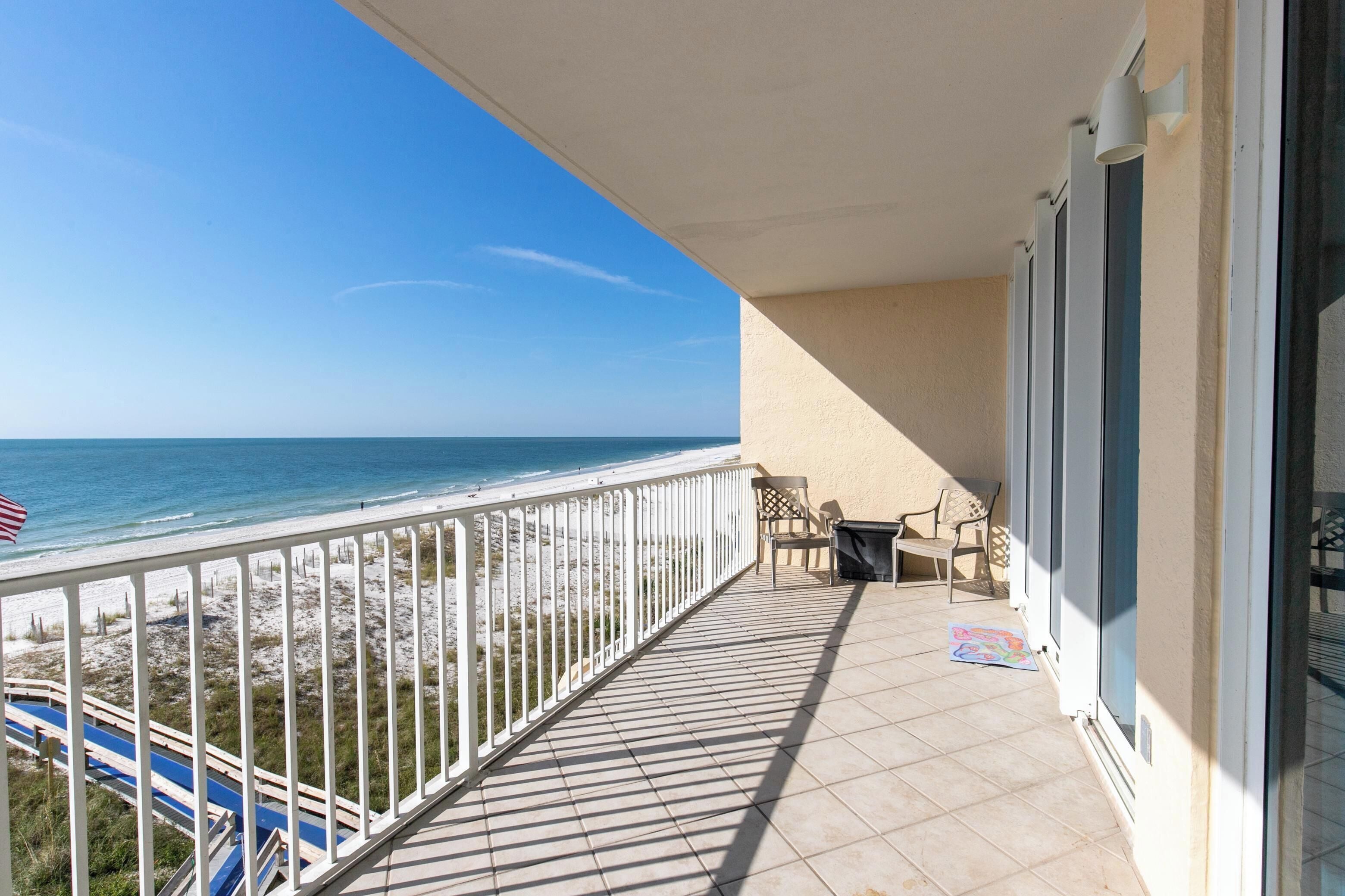 A balcony with a view of the beach and ocean.