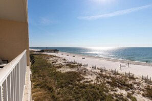 A balcony with a view of a beach, a pier, and the ocean.