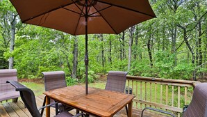 A wooden deck with a table and chairs, surrounded by a wooden railing and lush greenery. - 15 Courtland Drive (Sandwich)
