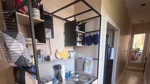 A compact kitchen with a built-in stove, a sink, and a small countertop. There are pots and pans hanging on the wall, and a window providing natural light. - Lake-Themed Private Guest Suite Gated Community Pet Friendly Near I-4 (Plant City)
