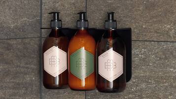 Three bottles of hair care products with pump dispensers mounted on a tiled wall.