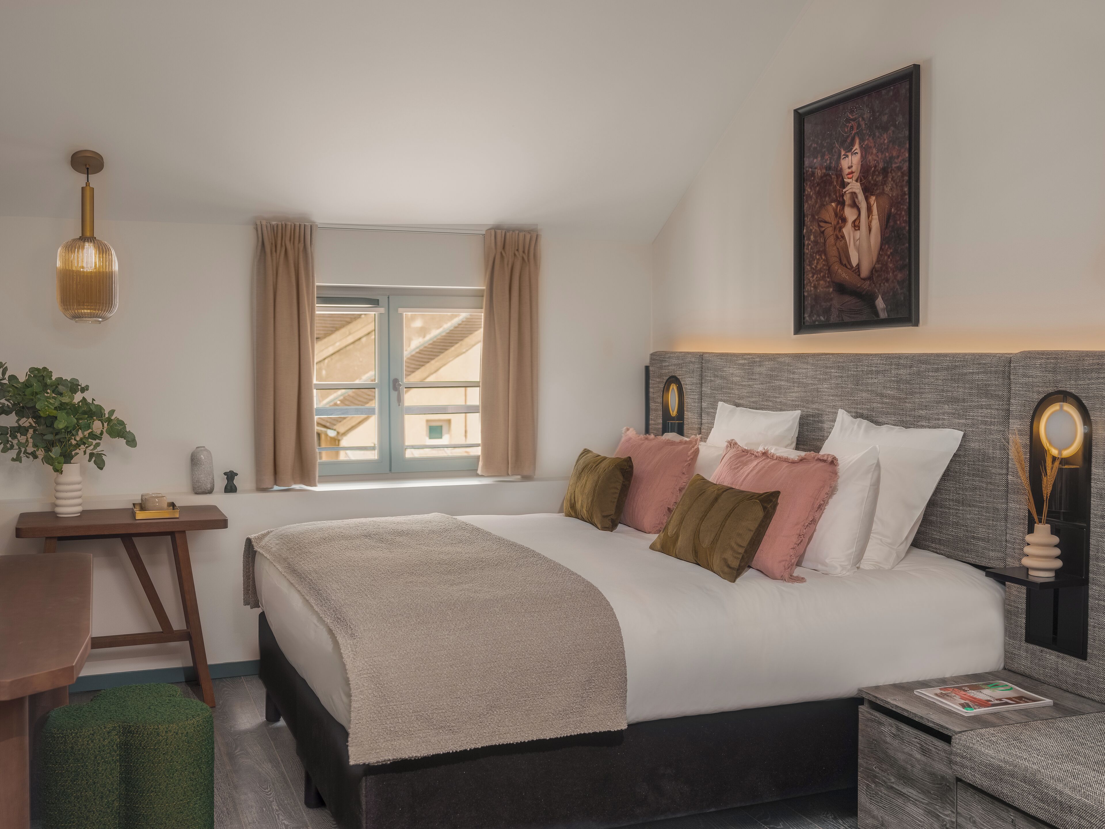 Un dormitorio ordenado con cama, mesitas de noche, una lámpara colgante y un cuadro en la pared.