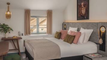 Un dormitorio ordenado con cama, mesitas de noche, una lámpara colgante y un cuadro en la pared.