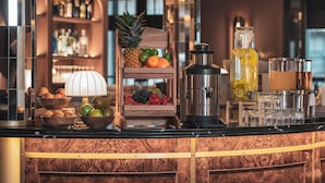 Eine Bar mit einer Obstauslage, einer Kaffeemaschine und einem Glasbehälter für Getränke.