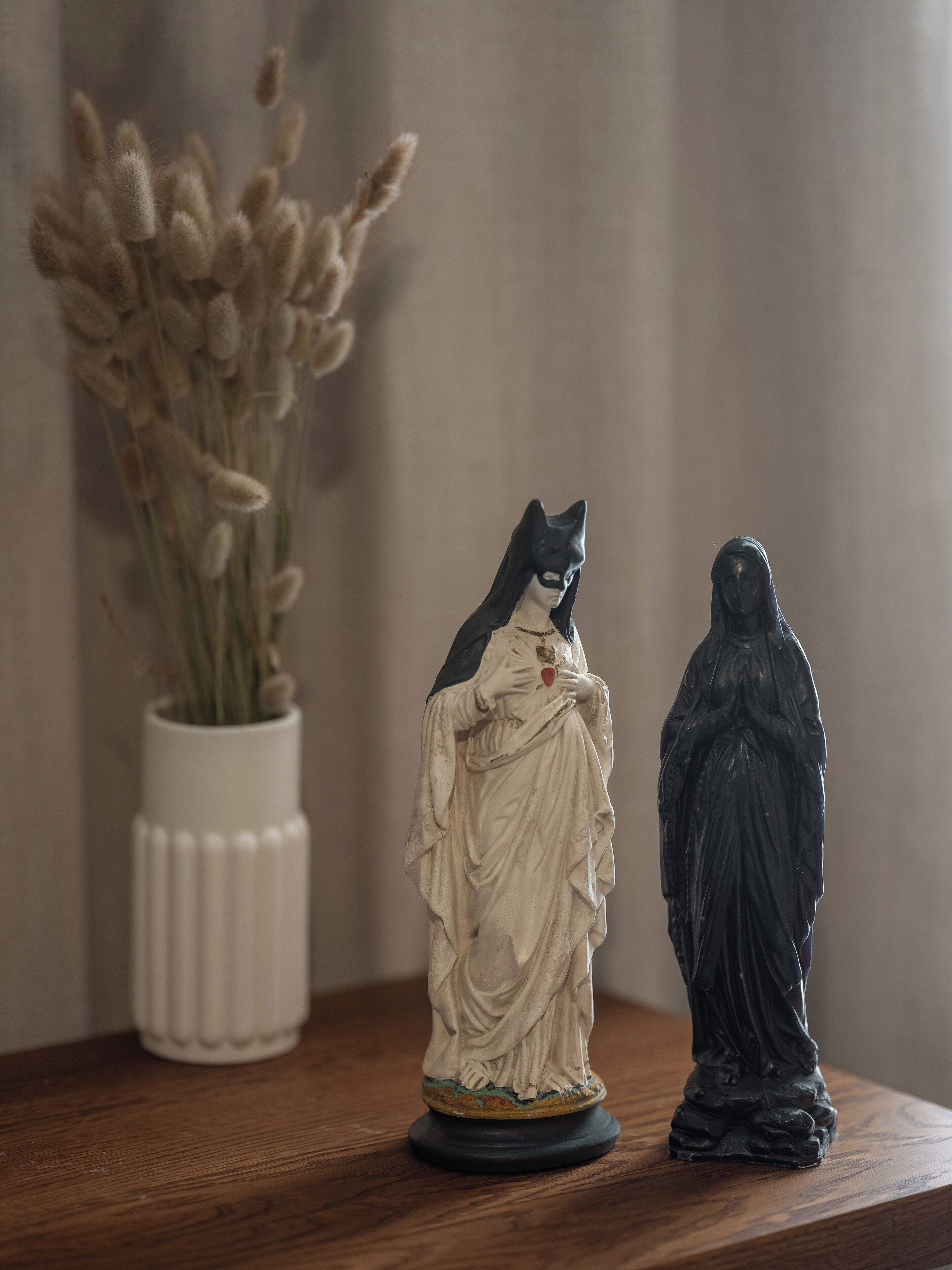 Una estatua de un gato y una figura sobre una superficie de madera.