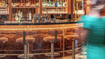 A bar area with stools, shelves of liquor bottles, and a counter.