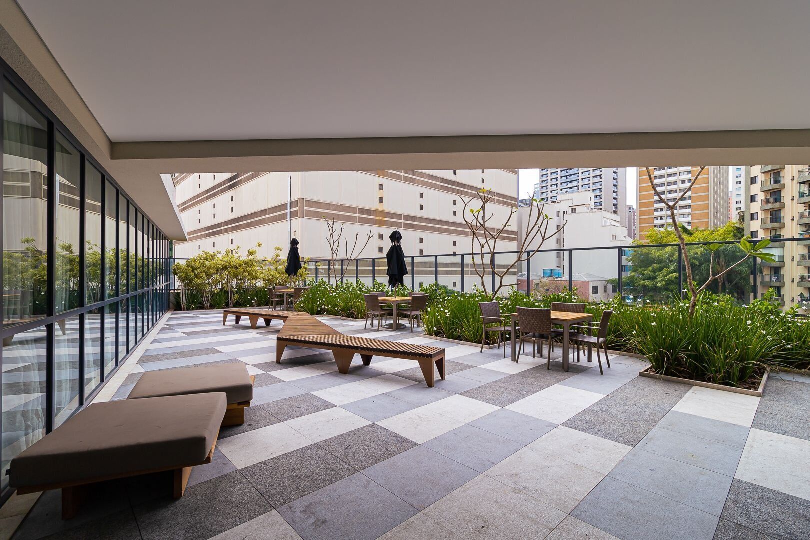 An outdoor terrace with seating, plants, and a view of surrounding buildings.