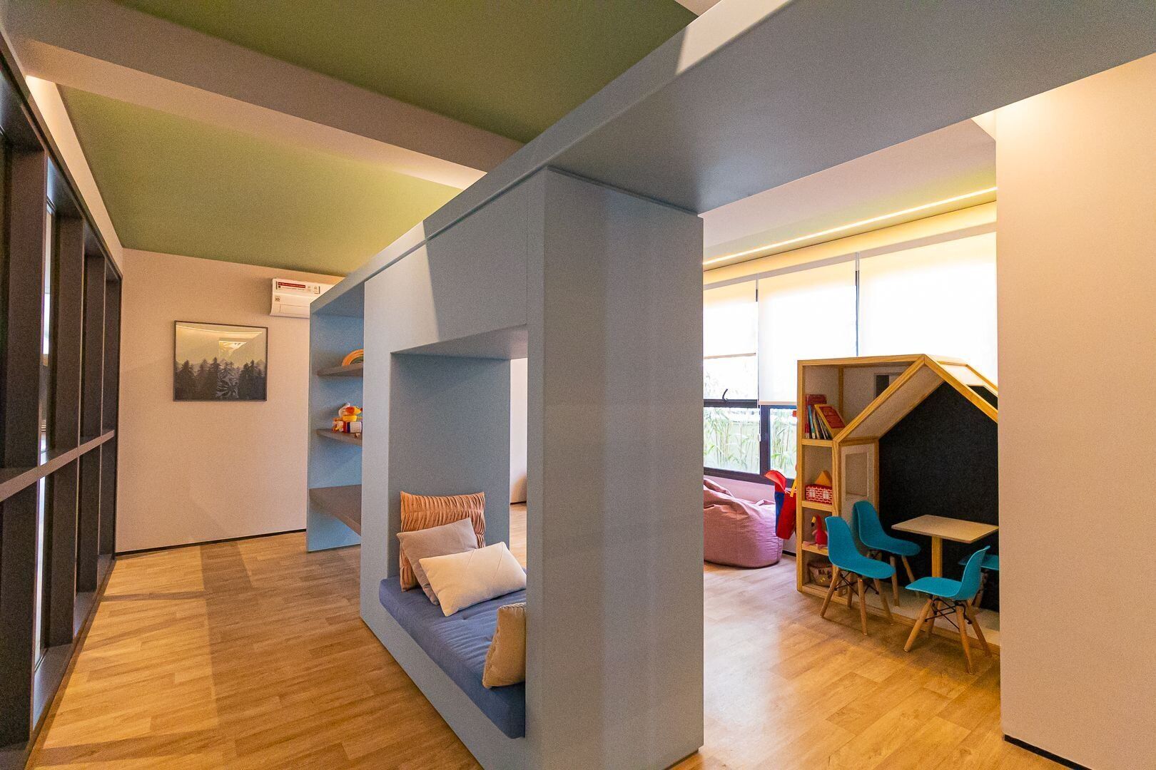 A modern interior with a wooden floor, a blue sofa, a bookshelf, and a small table with chairs.