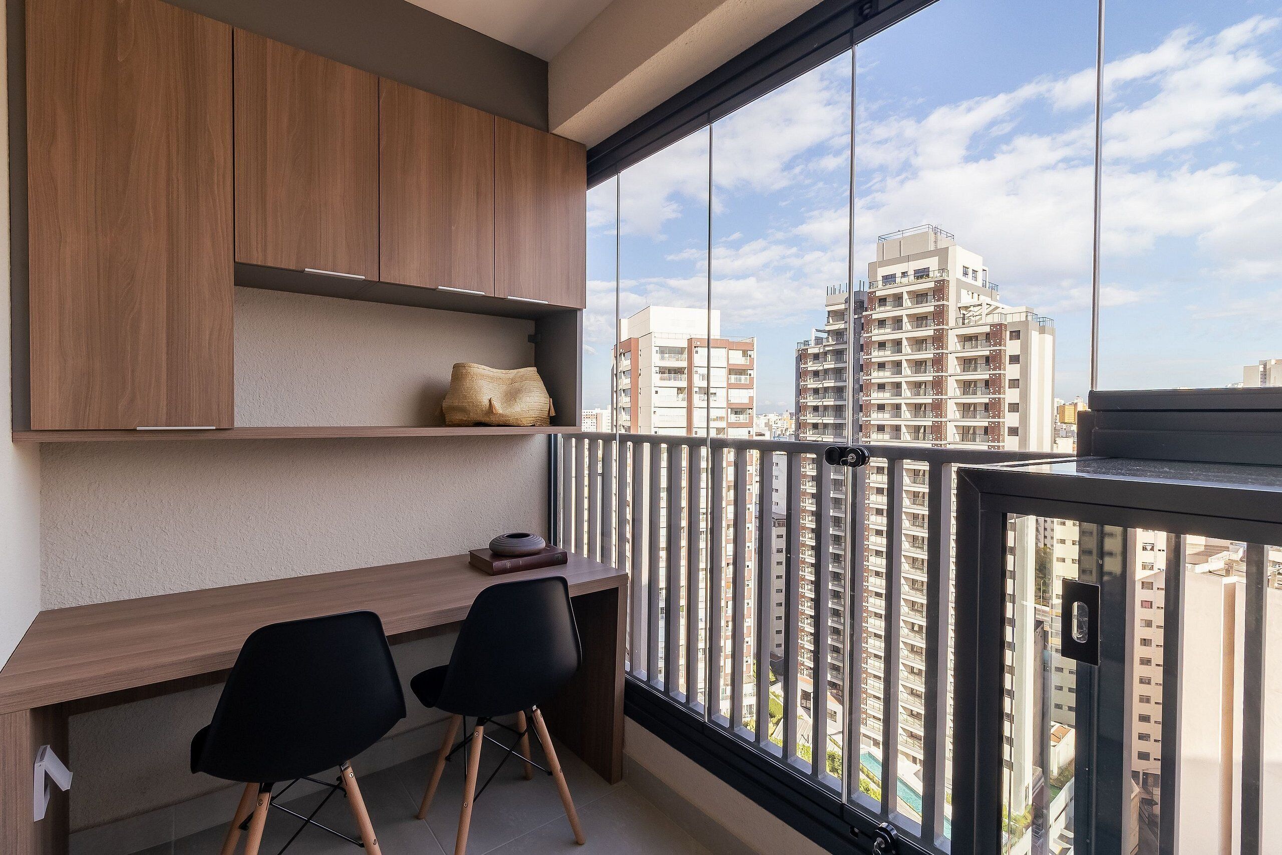 Un balcon équipé d’un bureau, de deux chaises et offrant une vue sur les immeubles de grande hauteur.