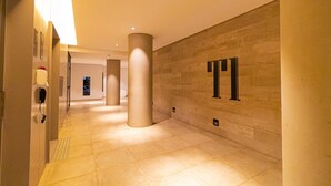 A modern hotel corridor with large pillars, a clean tiled floor, and a wall-mounted phone. - Vossa Bossa Facto (São Paulo)