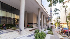 A modern building with large columns, a covered entrance, and a landscaped outdoor area with steps and greenery. - Vossa Bossa Facto (São Paulo)