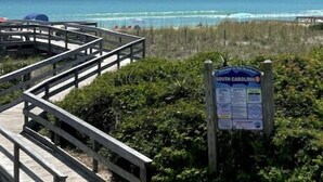 Un muelle de madera que conduce a una playa, con un cartel que indica Carolina del Sur.