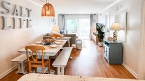 Un comedor con una mesa de madera, bancos y una lámpara colgante.