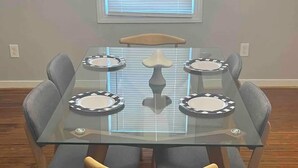 Una mesa de comedor con cuatro sillas, un adorno central y una ventana con persianas.