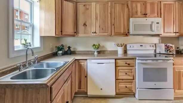 Una cocina con armarios de madera, un microondas blanco, un lavavajillas y un horno.