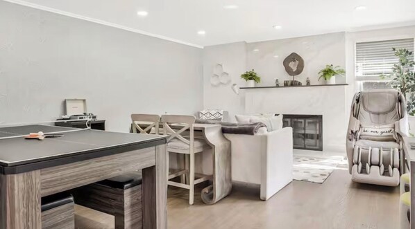 Un salon moderne comprenant un coin repas, un canapé, un fauteuil massant et une cheminée.