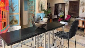 Un espace repas avec une table noire, des chaises en métal et une fresque colorée sur le mur.
