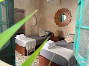 A room with two beds, a wooden-framed mirror, and a patterned floor. - Central & Bohemian House  Pool Yard (Mérida)