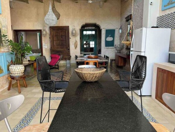 A cozy, open-plan living and dining area with a central island, black chairs, and a wooden dining table.