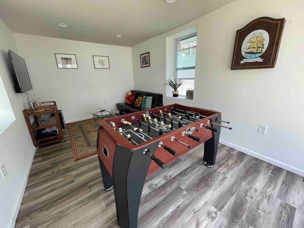 A room with a foosball table, a television, and a framed picture on the wall.