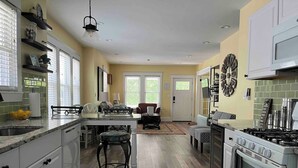 Una cocina amplia con una isla central, muebles blancos y una cocina grande.