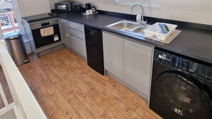 A compact kitchen with a dishwasher, a sink, and a window above the sink. - Stay Norwich Apartments Riverside House Apart-5 (Norwich)