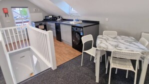 A compact kitchen with a dining area, white furniture, and a view of the outside. - Stay Norwich Apartments Riverside House Apart-5 (Norwich)