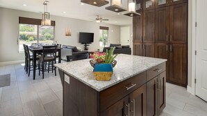 A modern kitchen with dark wood cabinets, a granite countertop, and a central island with a vase of flowers. - Entrada at Moab 420 and 424 and 428 (Moab)