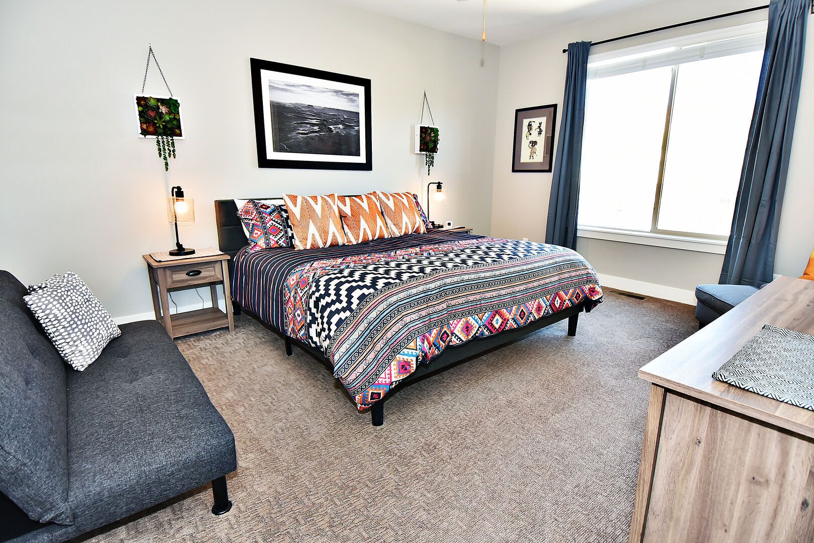A modern bedroom with a large bed, a bedside table, a chair, and a desk.