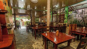 A restaurant with stone flooring, wooden tables and chairs, and a sign indicating Costa Rica. - COSTA LINDA ART HOSTEL  (Quepos)
