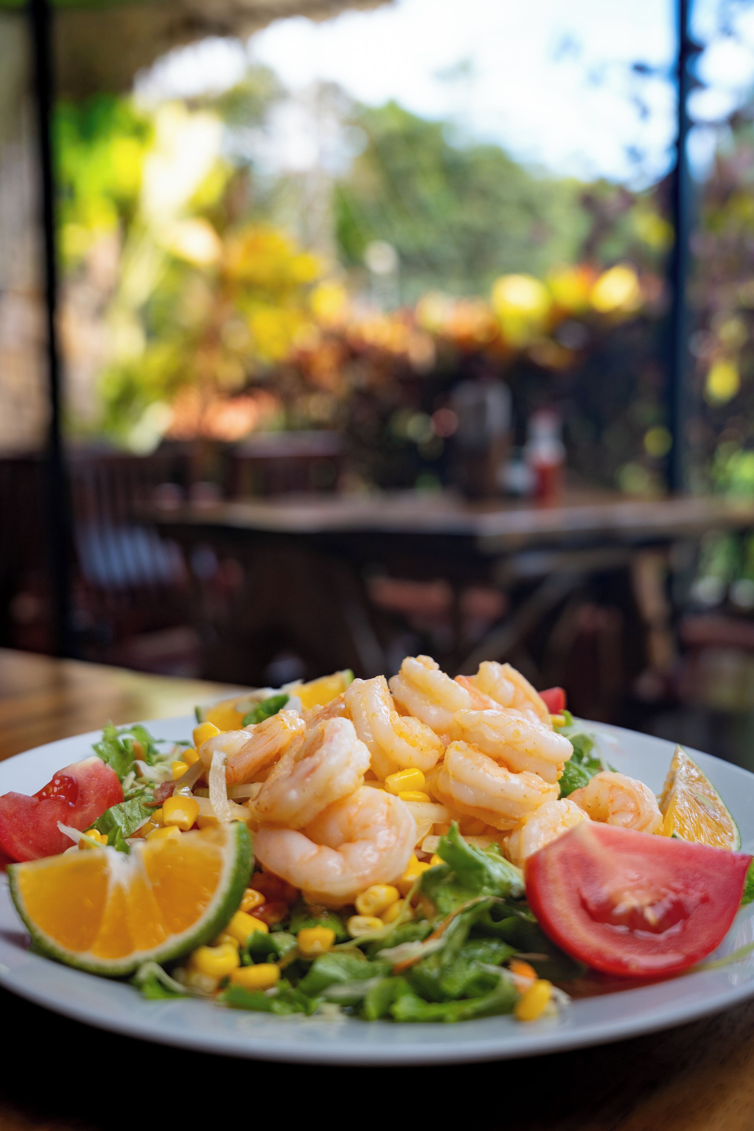Ensalada de camarones con maíz, lechuga y una rodaja de naranja.