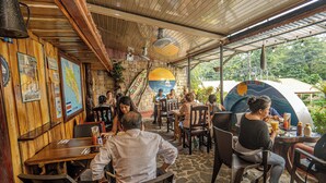 A restaurant with wooden walls, stone flooring, and a covered outdoor seating area. - COSTA LINDA ART HOSTEL  (Quepos)