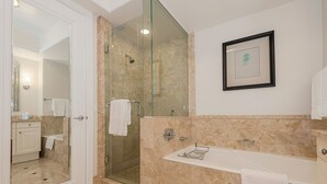 A modern bathroom with a glass-enclosed shower, a white sink with a towel, and a framed picture on the wall. - Elegant King Studio Suite + Kitchenette (Miami)
