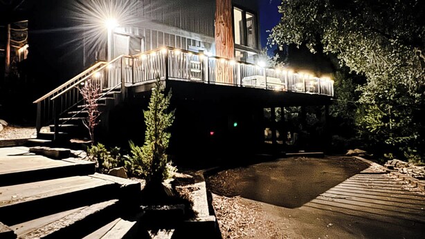 A modern building with a wooden deck and a staircase leading to a covered area.