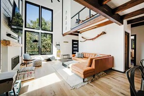 Ein modernes Wohnzimmer mit einem großen Fenster, einem Sofa, einem Couchtisch und einem Teppich.