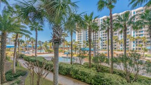 A resort with palm trees, a pool, and a large building in the background. - 1207 Amazing Lagoon Pool Views ~ Onsite Bar ~ Gym ~ Hot Tub ~ Book Sept 7th (Destin)