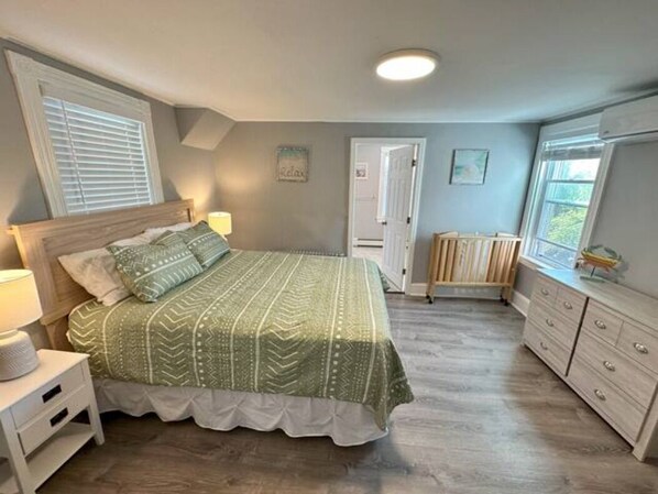 A bedroom with a bed, bedside table, dresser, and a window. - Beach, harbor, ferry & food-Prime Hyannis location (Barnstable)