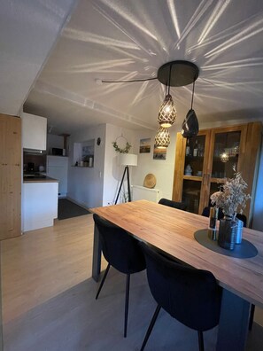 A modern kitchen with white cabinets, a wooden dining table, and black chairs. - Großes Meer (Südbrookmerland)