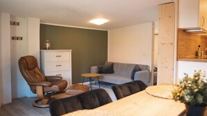 A cozy living room with a leather chair, a grey sofa, a small round table, and a wooden cabinet. - Großes Meer (Südbrookmerland)