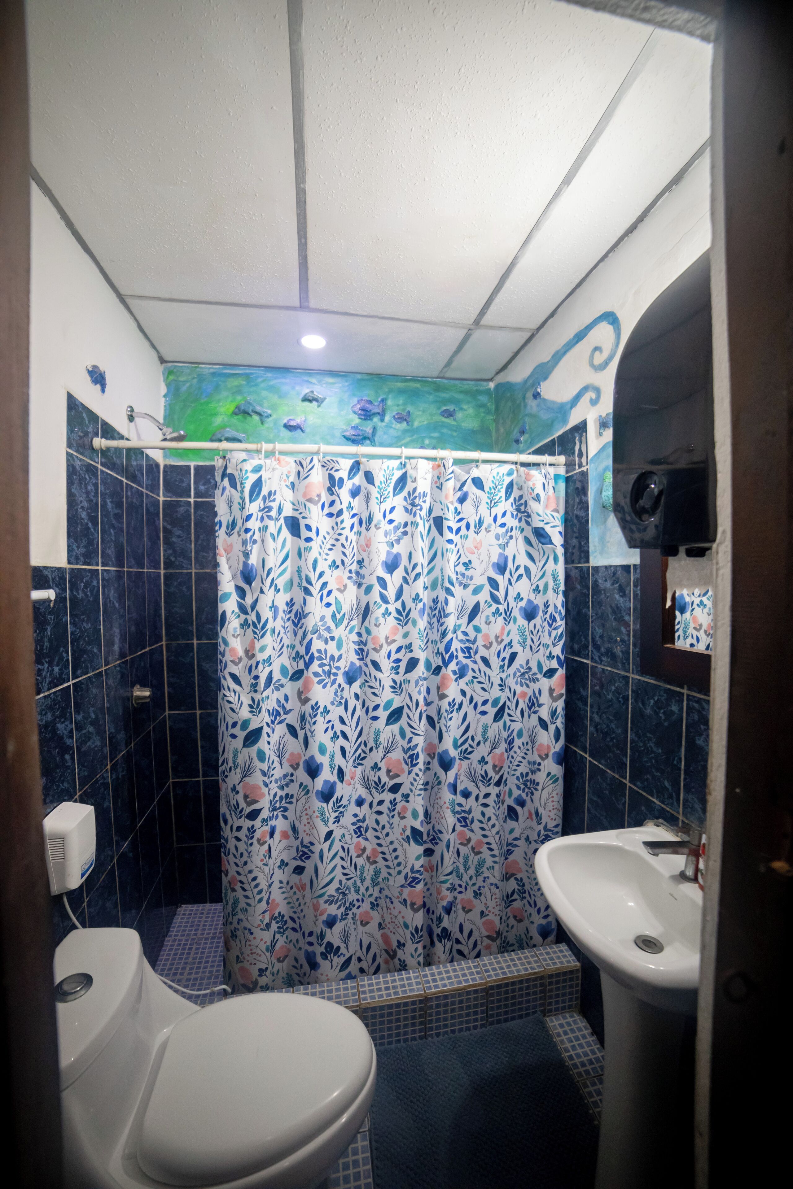 A bathroom with a shower curtain, a sink, and a toilet.