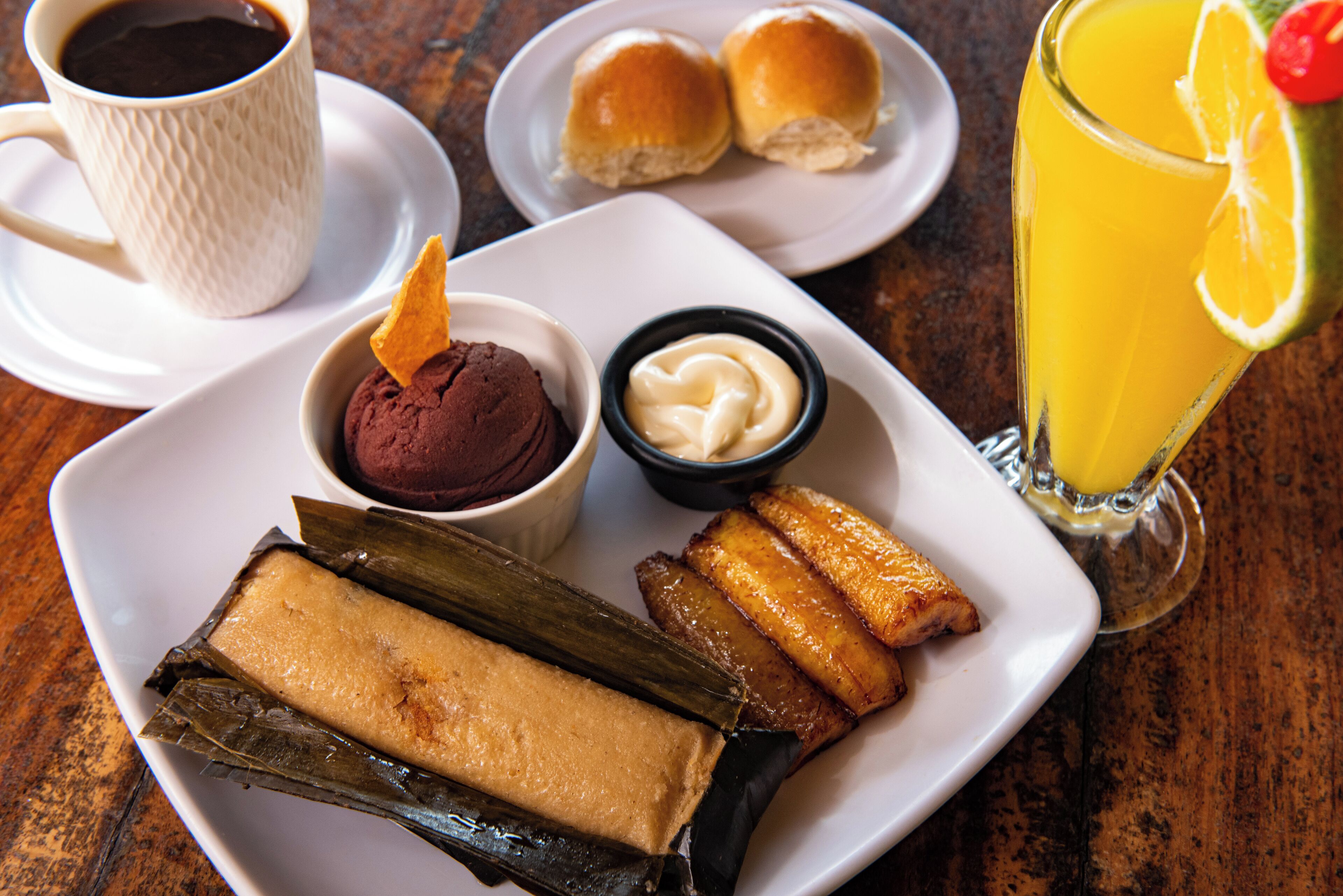 En tallerken med tamales, en kop kaffe og et glas appelsinjuice.