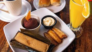 En tallerken med tamales, en kop kaffe og et glas appelsinjuice.
