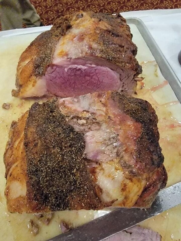 A roasted ham with a crispy exterior and a pink center, served on a white plate. - Crookston Inn & Convention Center (Crookston)