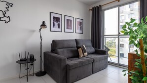 A modern living room with a grey sofa, a floor lamp, and three framed pictures on the wall. - Charm in Barra da Tijuca Great Wifi Sa508 (Rio de Janeiro)