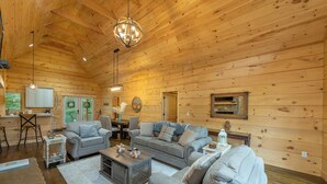 Eine geräumige Holzhütte mit einer gemütlichen Wohnbereich, der zwei Sofas, einen Couchtisch und einen Esstisch bietet.