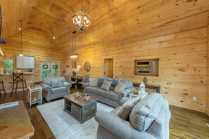 A spacious wooden cabin with a cozy living area featuring two sofas, a coffee table, and a dining table.