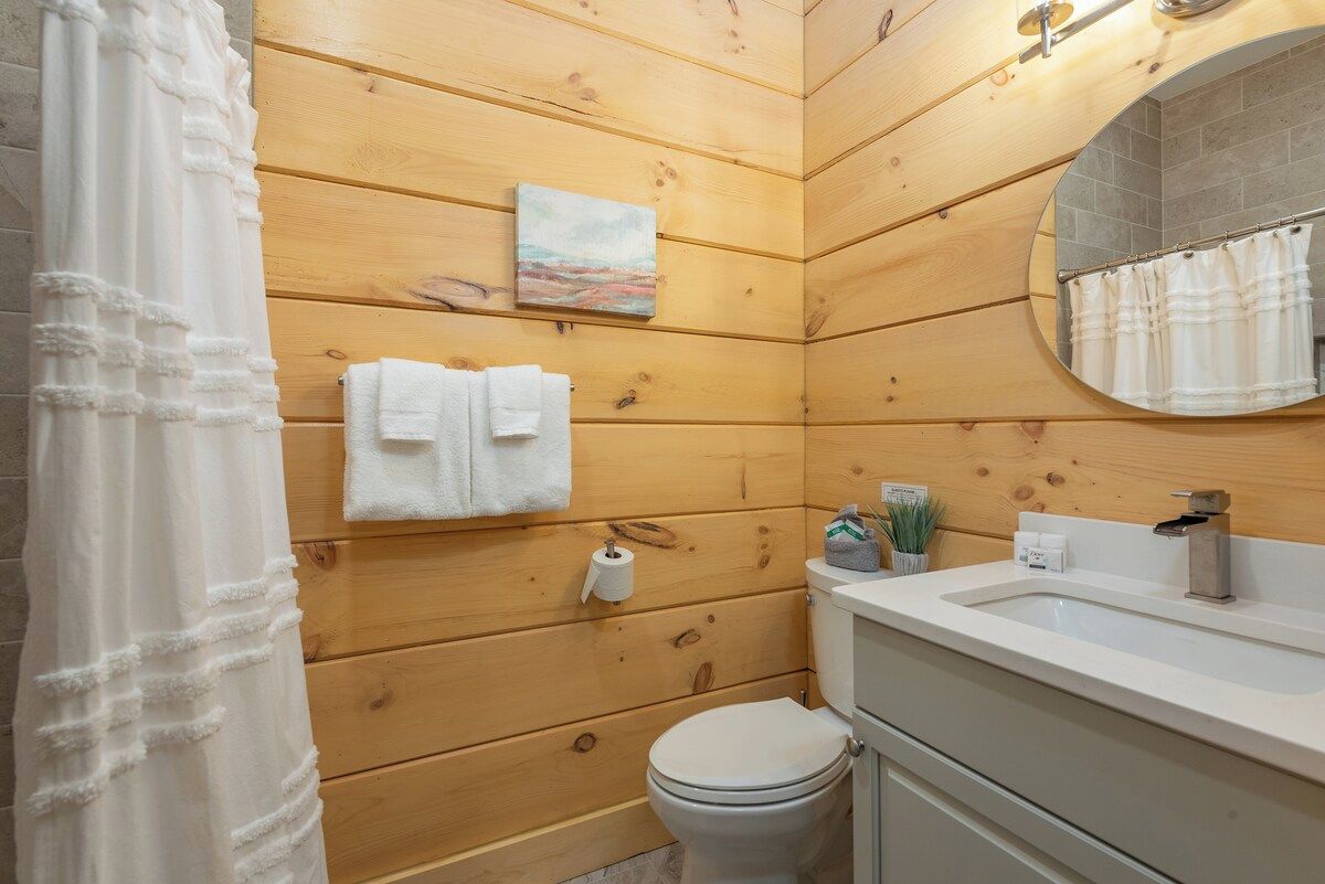 Une salle de bain aux murs lambrissés, équipée de toilettes, d’un lavabo et ornée d’un tableau.