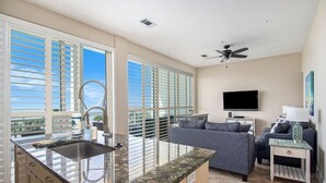 Un espacio habitable moderno con una isla de cocina, un sofá, un televisor y un ventilador de techo.