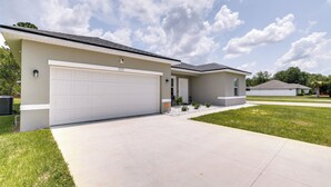 A modern two-story house with a large garage, a well-maintained lawn, and a clear sky. - Bright, Pet-Friendly Home: 16 Mi to Downtown Ocala (Ocala)