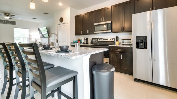 A modern kitchen with dark cabinets, stainless steel appliances, and a granite countertop. - Bright, Pet-Friendly Home: 16 Mi to Downtown Ocala (Ocala)
